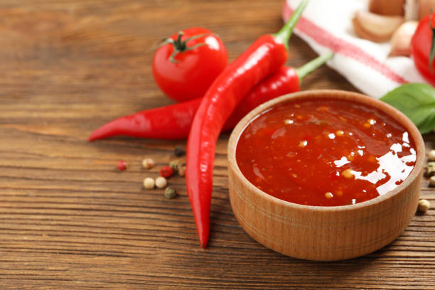 istock Spicy chili sauce and ingredients on wooden table, space for text 1327043241