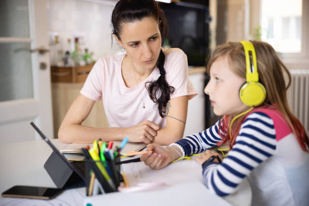 istock Mother helping her elementary age daughter with online learning 1327043856