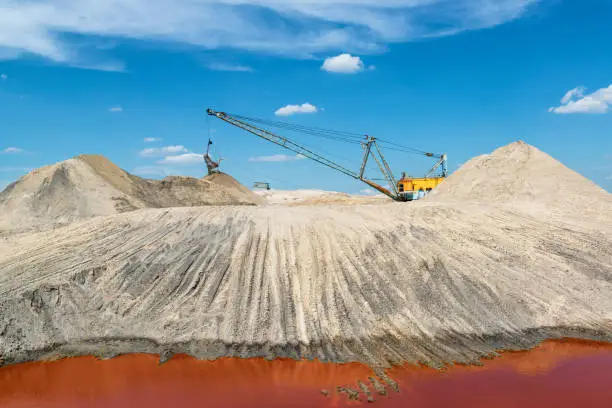 "Another planet" industrial landscape with a walking excavator working in a titanium quarry with intense red color of water