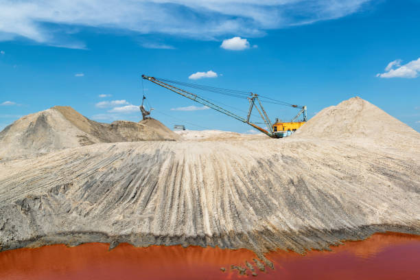 krajobraz przemysłowy z chodzącą koparką pracującą w kamieniołomie tytanu o intensywnym czerwonym kolorze wody - titanium zdjęcia i obrazy z banku zdjęć