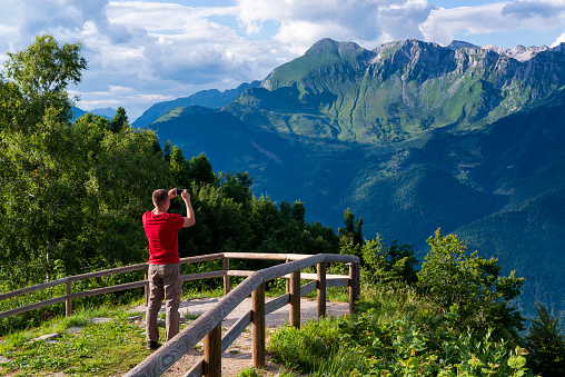 A tourist admires the scenery of Julian Alps in Slovenia and takes photos