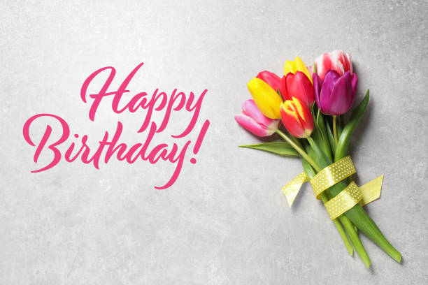 Happy Birthday! Beautiful spring tulips on light grey stone table, top view