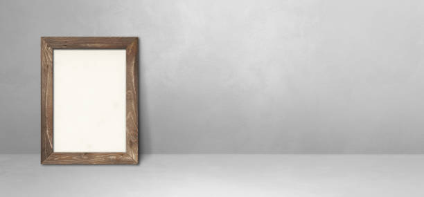 istock Wooden picture frame leaning on a light grey wall. Horizontal banner 1327046064