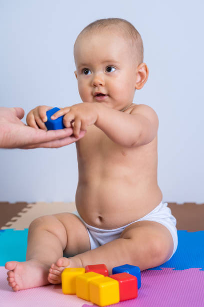 le bambin prend un cube de plastique bleu des mains de son père. - playground cute baby blue photos et images de collection