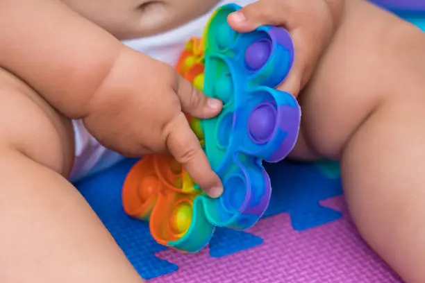 Photo of Baby 7-12 months old plays with a fashionable silicone toy pop it