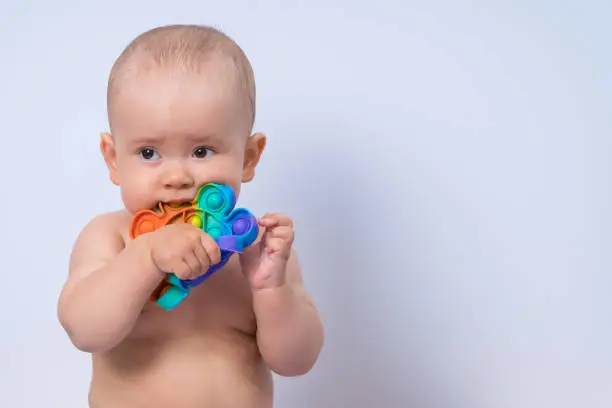 Photo of Newborn baby 7-12 months old bites a modern pop it toy