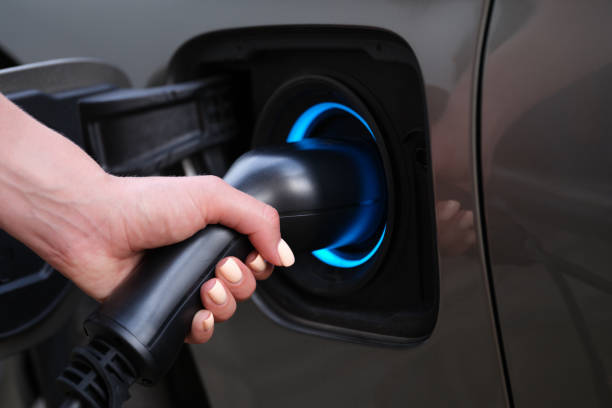 Woman charging car using electric plug closeup Woman charging car using electric plug closeup. Environmentally friendly fuel concept motor living stock pictures, royalty-free photos & images