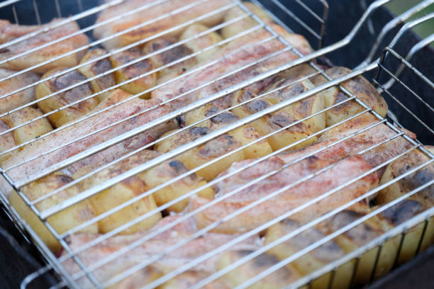 Roast pork and potatoes on wire rack over fire closeup. Home cooking kebabs concept