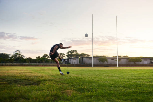in voller länge schuss eines hübschen jungen sportlers kickt einen rugby-ball während einer frühen morgen-trainingseinheit - rugby field stock-fotos und bilder