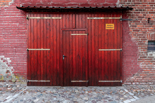 Bright red wood, lightly textured and weathered. Red aged door wit a dark roof.