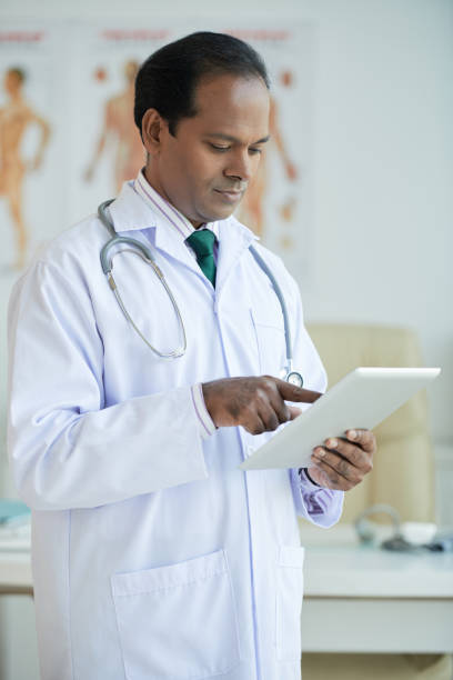 Confident Physician Reading Anamnesis Serious confident physician reading anamnesis of patient on tablet computer anamnesis stock pictures, royalty-free photos & images