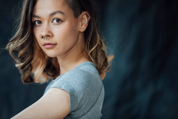 A Cool Female A young contented, trendy woman posing for the camera. She is standing in front of a backdrop. septum piercing stock pictures, royalty-free photos & images