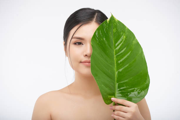 istock Young Woman with Big Lush Leaf 1327060695