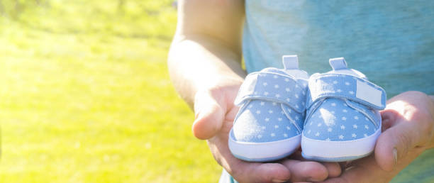 dad waiting birth of him first son. man holding small blue baby shoes in hands. happy parents concept. pregnant concept. - human pregnancy couple prenatal care heterosexual couple imagens e fotografias de stock