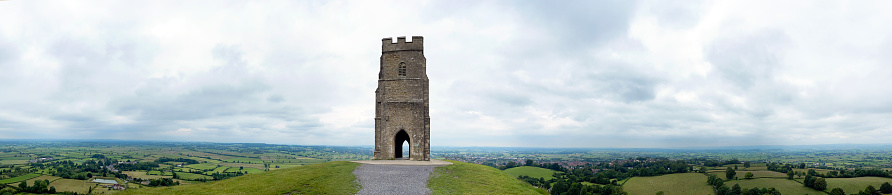 Despite the constantly changeable weather, wild flowers and cultivated blooms appear in a multitude of colours to brighten the dramatic landscape of the Somerset Levels and landmarks such as Glastonbury Tor on one of the  steep ridges of the outdoors countryside scenery during summer in Somerset, England, UK