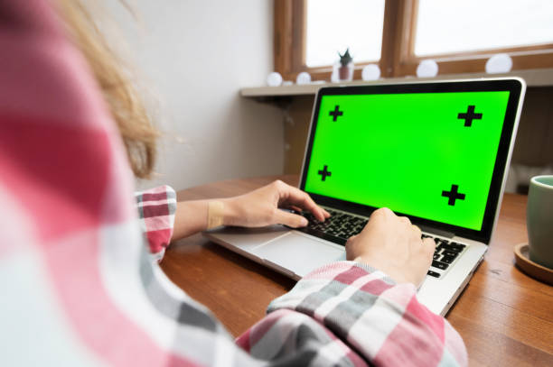 istock Woman using laptop with green screen. Business, communication, freelance and internet concept. Working at a laptop at home 1327064107