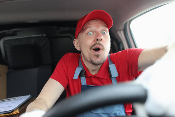 istock Surprised male courier in uniform is driving car 1327065036