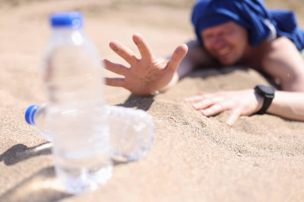 homme déshydraté rampant sur le sable pour une bouteille d’eau potable gros plan - thirsty desert men reaching photos et images de collection