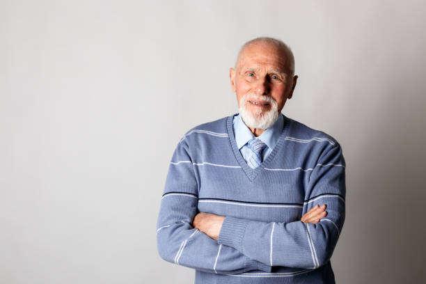 istock Old man looking at the camera on gray background with copy space. 1327065181