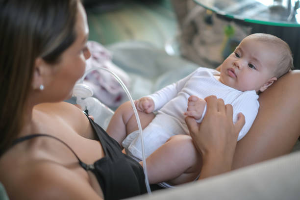 nuova madre che pompa il latte materno a casa - sucking asian ethnicity baby mother foto e immagini stock