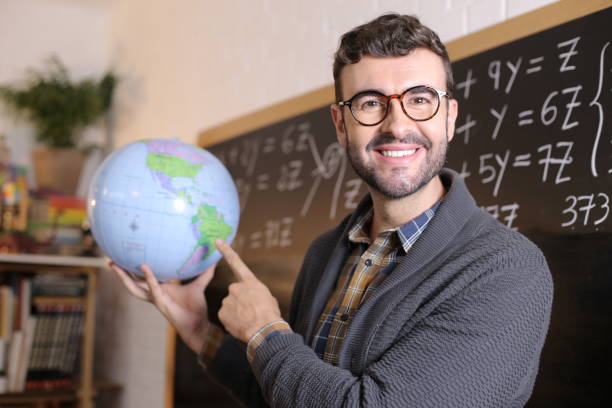 Geography teacher showing the globe in classroom.