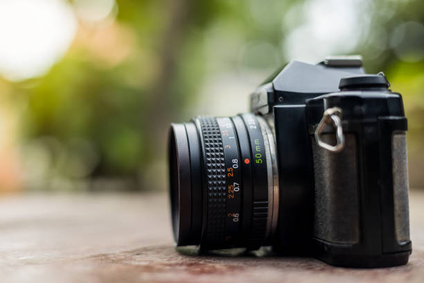 istock An old black film camera against a blurry green leaf background. 1327069669