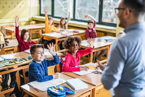 istock Large group of happy students raising hands to answer the teacher's question on a class. 1327072060