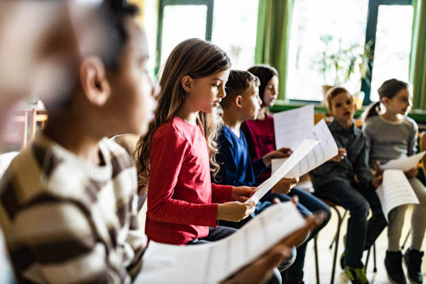 istock School kids practicing with sheet music on a class at school. 1327072337