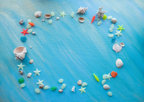 Seashells summer background. rectangular frame. Many different seashells, starfish on a background of turquoise shimmering strokes. Creative flat lay banner, workspace composition with seashell and pebbles, copy space photo. High quality photo