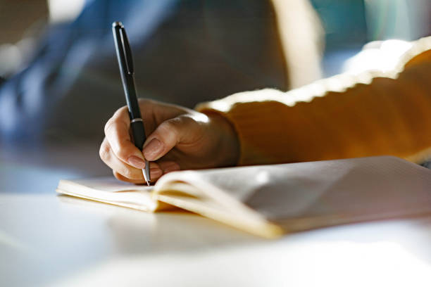 istock Close up of college student writing an exam on a class at school. 1327073191