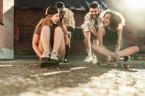 istock Playful couples having fun on skateboards on the street. 1327074572
