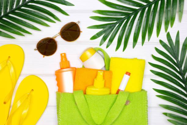 Summer sea beach vacation creative concept. Towels, face and body sunscreen cosmetic skincare products in eco bag, flip flop sandals, sunglasses. Top view, flat lay Summer sea beach vacation creative concept. Towels, face and body sunscreen cosmetic skincare products in eco bag, flip flop sandals, sunglasses. Top view, flat lay uv protection photos stock pictures, royalty-free photos & images