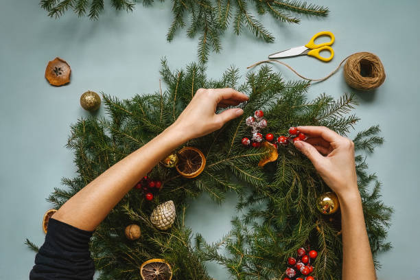 mujer haciendo corona de navidad hecha a mano. vista superior. - montada fotografías e imágenes de stock