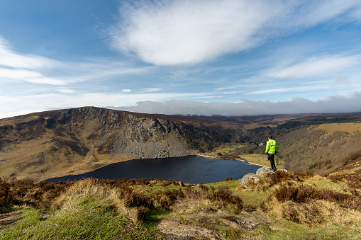 young man cyclist standing on rock with lough tay lake Ireland in the background