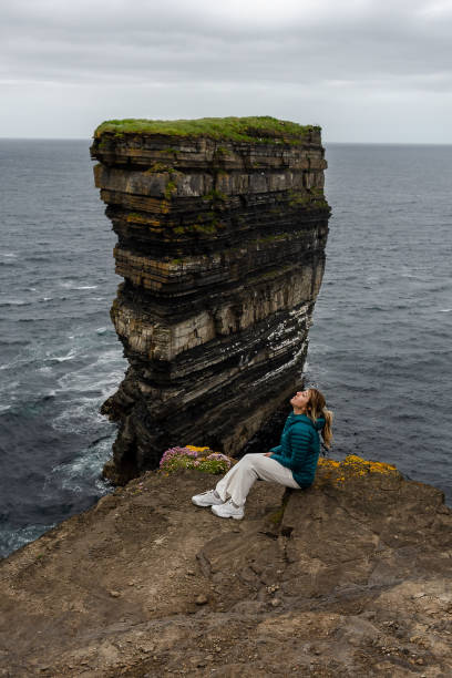 istock Woman sitting on cliff at Downpatrick Head Ireland 1327078563