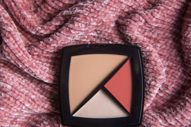 istock Make up face contouring kit: foundation concealer, highlighter and color blush. Decorative cosmetics in black box on pink background. Make up and beauty concept. 1327078649