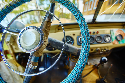 Vintage interior of an old car with a retro dashboard and steering wheel in a PVC cover.