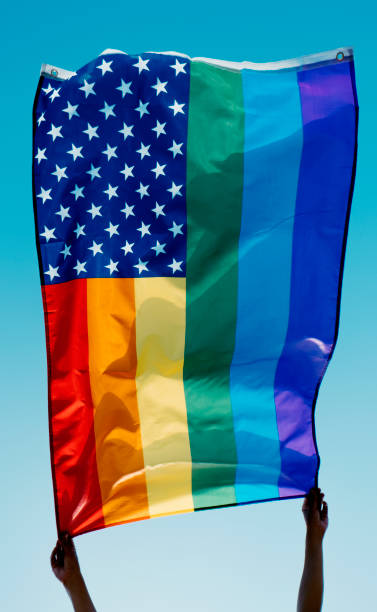 someone waves a rainbow US flag on the sky