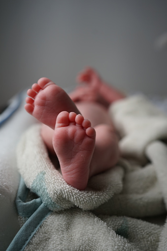 Close-up of little legs of a newborn baby on rug. Tiny foot of newborn baby.