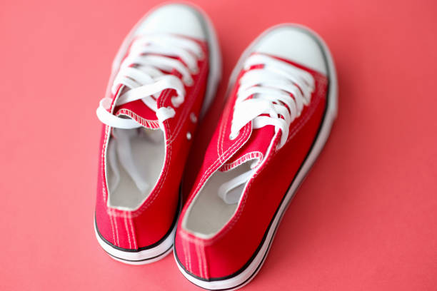 istock Red sneakers with white laces against red background closeup 1327081976