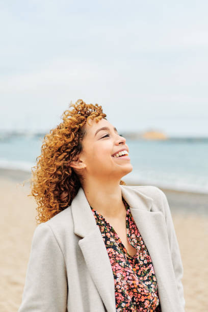 istock Curly woman smiling on the beach 1327082318