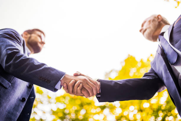 istock Two businessmen shaking hands in nature. 1327083195