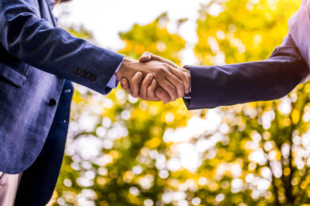 istock Two businessmen shaking hands in nature. 1327083447