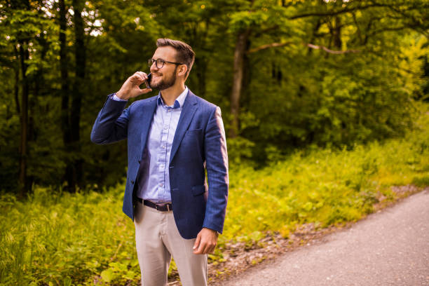 istock Happy young businessmen talking on phone while relaxing in nature. 1327085358