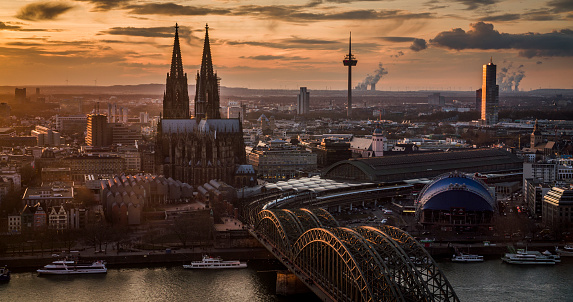 Cologne cityscape with cologne central station, Hohenzollern bridge, philharmonic, television tower and famous Cologne Cathedral in moody sunset light at dusk. Germany, Europe.