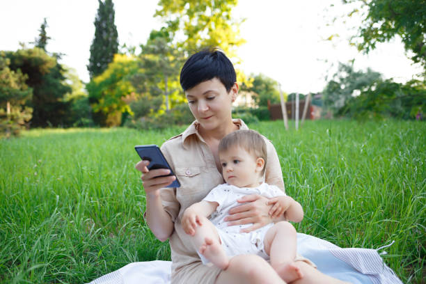istock little boy sitting on mom's lap pulling to mobile phone 1327086882