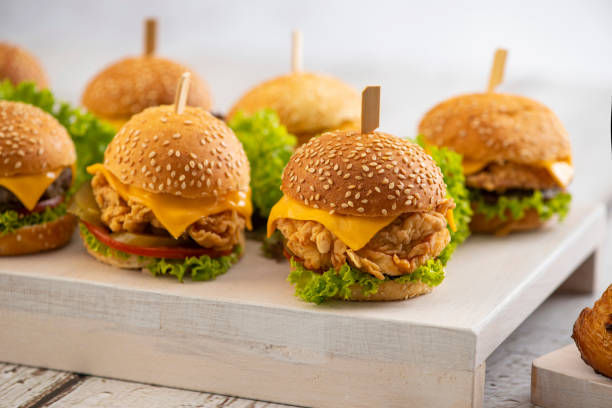 ensemble de mini-hamburgers de bœuf et de poulet avec du fromage et de la laitue avec des bâtonnets sur un fond en bois - sandwich food lunch chicken photos et images de collection