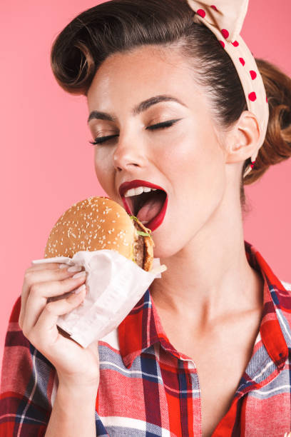 istock Young pin-up woman eating burger. 1327087829