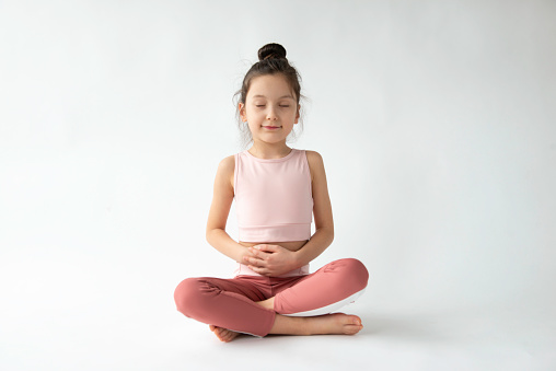 Cute girl doing breathing exercise in front of white background.