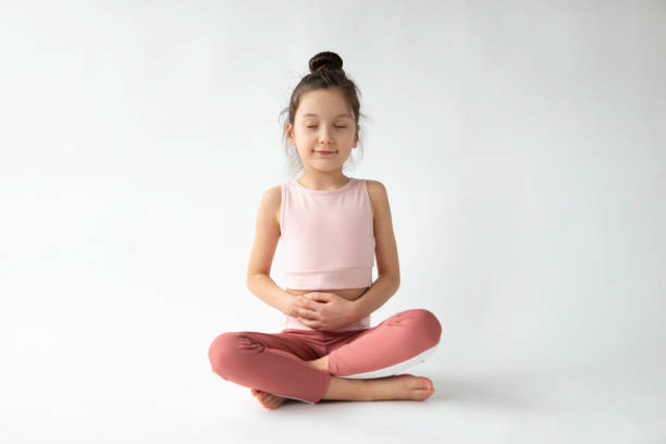 Cute Girl Doing Breathing Exercise Cute girl doing breathing exercise in front of white background. mindfulness children stock pictures, royalty-free photos & images
